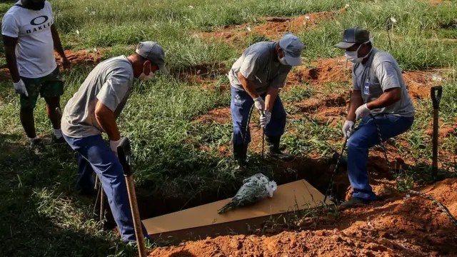 Des fossoyeurs abaissent le cercueil de Maria de Lourdes Moreira Cruz, 58 ans, décédée des suites de la maladie du coronavirus (COVID-19) lors de son enterrement, au cimetière Campo Santo de Porto Alegre, au Brésil, le 6 avril 2021.