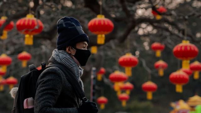 A man wears a protective facemask to help stop the spread of a deadly SARS-like virus which originated in the central city of Wuhan, as he walks past Lanterns at Jingshawn park overlooking the Forbidden Cityin Beijing on January 25, 2020