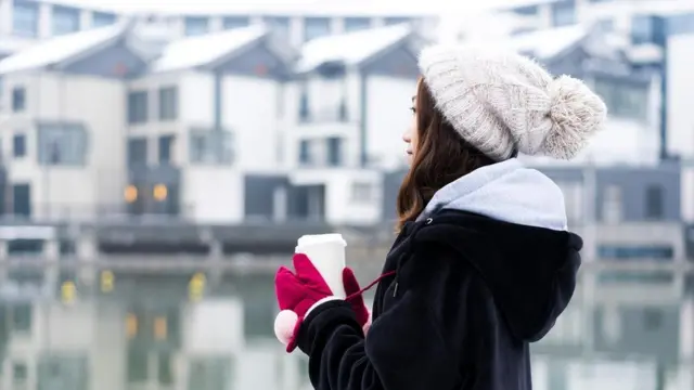 mujer sosteniendo un café en invierno