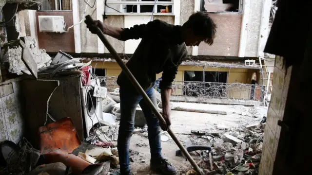 A young man cleans a damaged house in the besieged town of Douma, Eastern Ghouta, Damascus, Syria February 25, 201