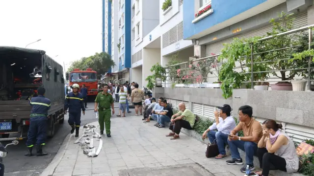 Người dân ngồi trầu trực bên ngoài Carina Plaza, phân vân khi nào họ có thể quay trở về nhà