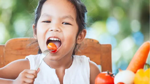 Menina comendo legumes