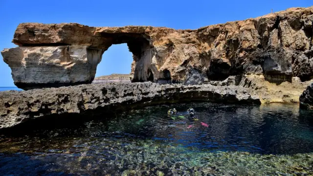 Divers are seen in front of the natural arch The Azure Window at Dwejra Bay on 20 May, 2014