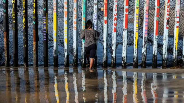 Persona frente a una reja en la frontera entre México y Estados Unidos