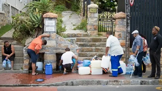 Personas hacen fila para recoger agua de una fuente en Ciudad del Cabo.