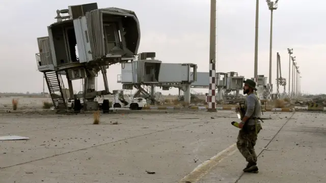 Un combattant fidèle au gouvernement d'accord national libyen (GNA) reconnu par l'ONU se tient sur le tarmac de l'aéroport international de Tripoli après sa capture par les forces rivales fidèles à l'homme fort Khalifa Haftar, le 3 juin 2020.