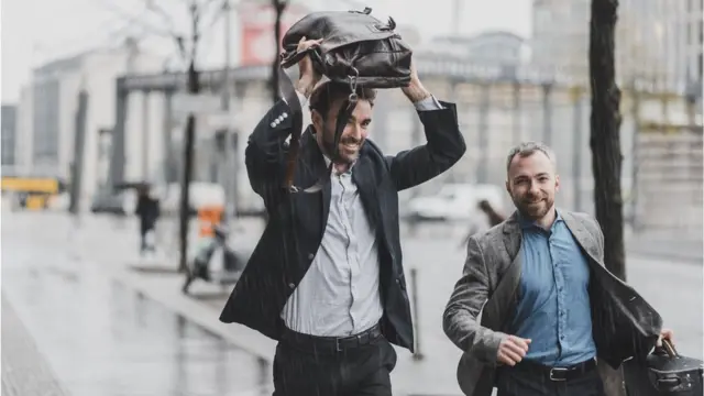 Hombres corriendo bajo la lluvia.