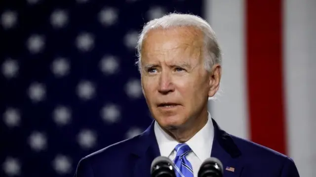 Joe Biden discursa com a bandeira americana ao fundo