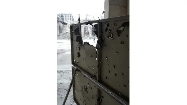 Sebuah pintu masuk tambahan di masjid yang penuh dengan lubang peluru. Jeremy Bowen menduga, pintu ini digunakan sebagai jalan tembus yang aman bagi para pemberontak.