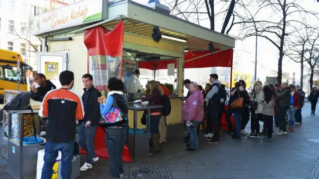 Un puesto callejero de kebabs y una fila de gente