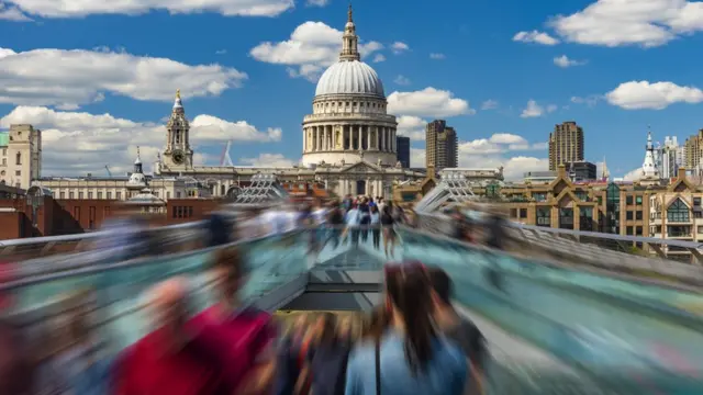 Time-lapse image depicting pedestrians in motion on the Millennium Bridge