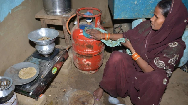 En Inde, une femme se prépare à cuisiner avec une bouteille de gaz de pétrole liquéfié.