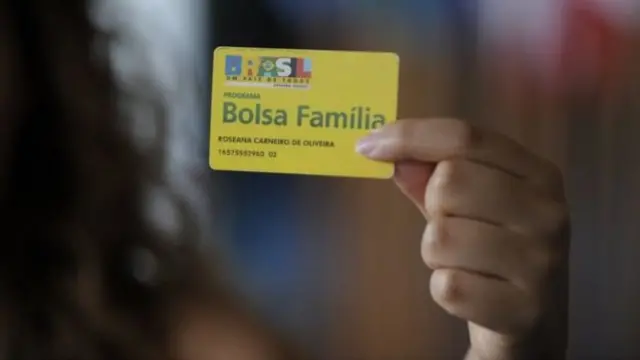 Mulher segura cartão do Bolsa-Família