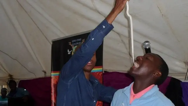 Puel Mnguni akiingiza nyoka katika kinywa cha muumini