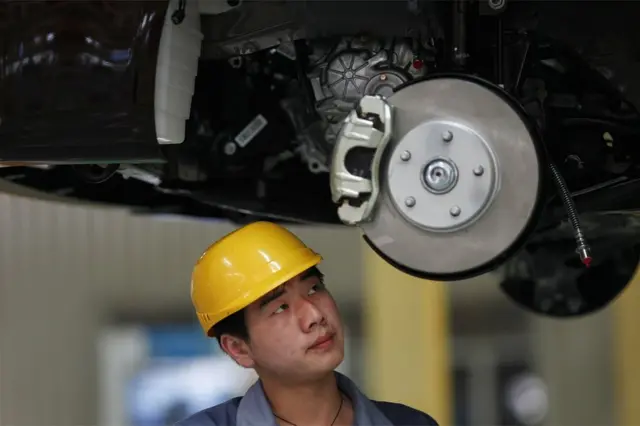 Un empleado mira a un vehículo en proceso de ensamblaje en la planta de Geely en Cixi, en la provincia china de Zhejiang, el 21 de junio de 2012.