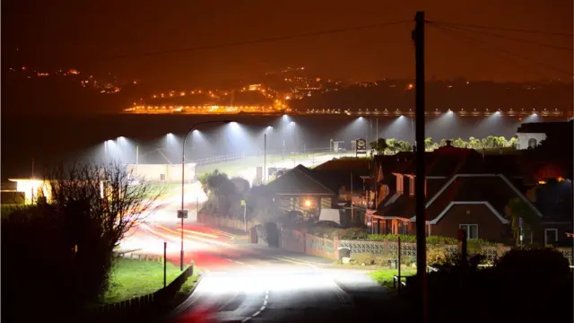 Postes de luz iluminando una carretera.