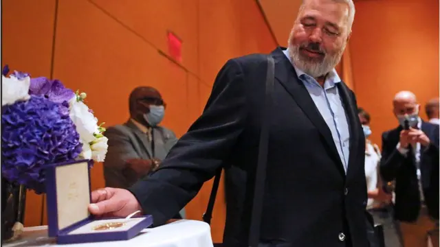 Dmitry Muratov pose to members of the media before he auctioned his Nobel Peace Prize