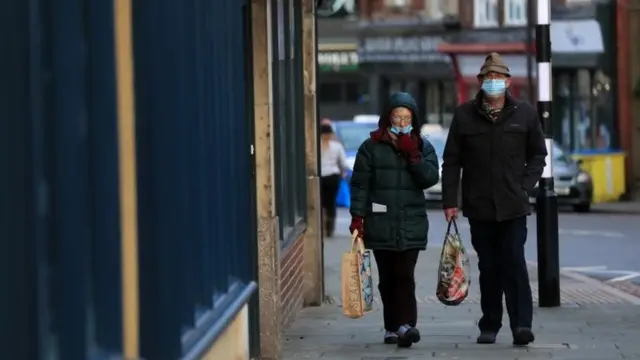 Two people wearing face masks walk through the quiet streets in Grantham, Lincolnshire
