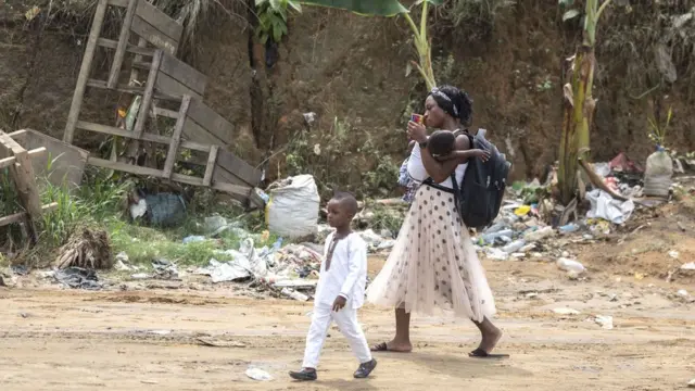 Une mère marche avec ses enfants dans une rue de Douala, le 9 janvier 2022.