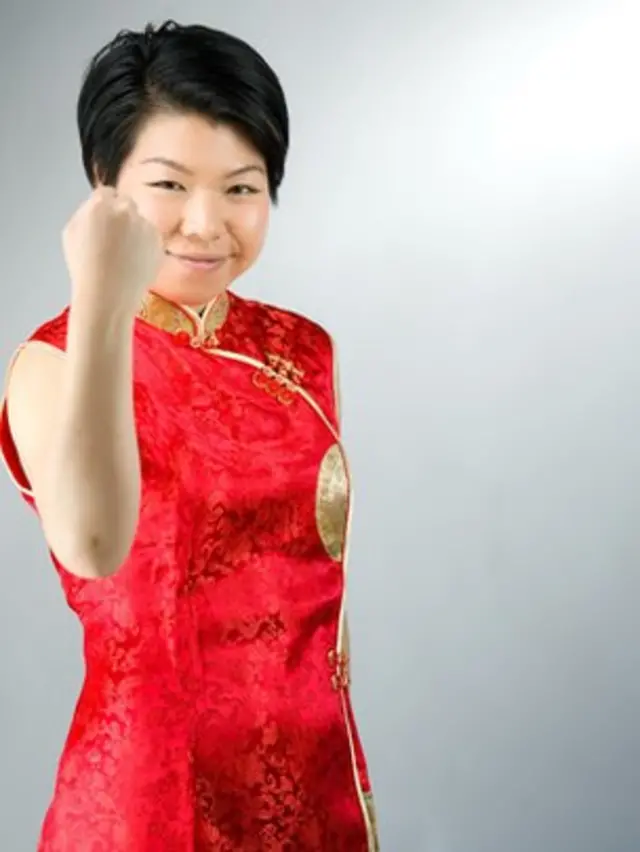 Una mujer china con el puño cerrado, con expresión de haber logrado un objetivo