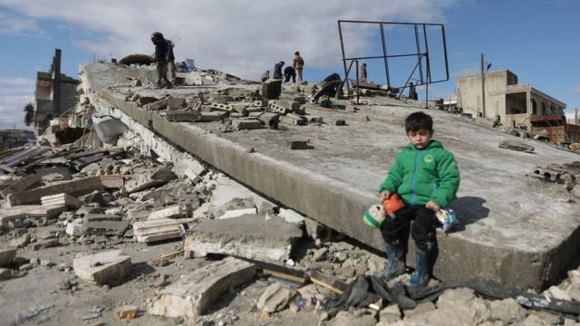 Сирийский мальчик на обвалившемся здании в городе Азаз на границе с Турцией 7 февраля 2023 года