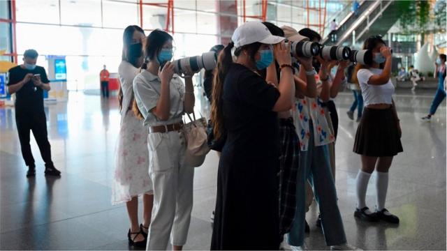 Fans holding cameras wait for celebrities at Beijings Capital Airport in Beijing on August 25, 2021.