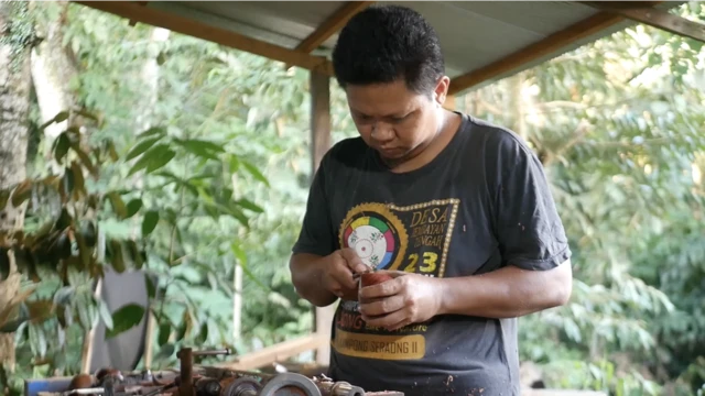 Norsyamdani, 36 tahun, sedang membuat gasing - dari memotong, memahat hingga mengikis kayu.
