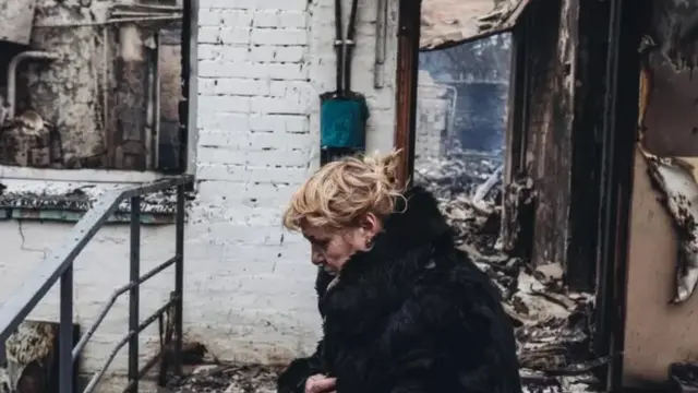 Une femme prostrée au mileu de ruines
