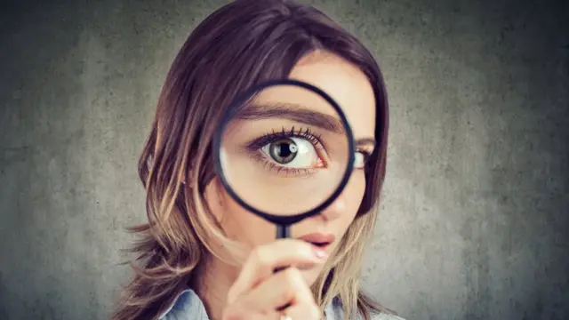 Mujer sosteniendo una lupa.