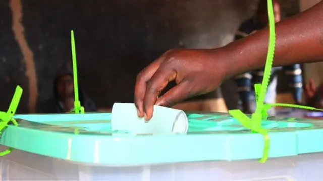 Ọwọ kan n fi iwe idibo sinu apoti