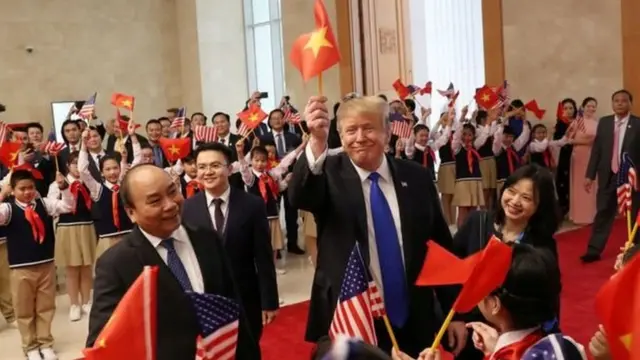 Trump waves a Vietnamese flag during a meeting with Vietnam's Prime Minister