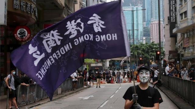 A masked anti-government protester holds a flag supporting Hong Kong independence during a march against Beijing"s plans to impose national security legislation in Hong Kong, China May 24, 2020. REUTERS/Tyrone Siu