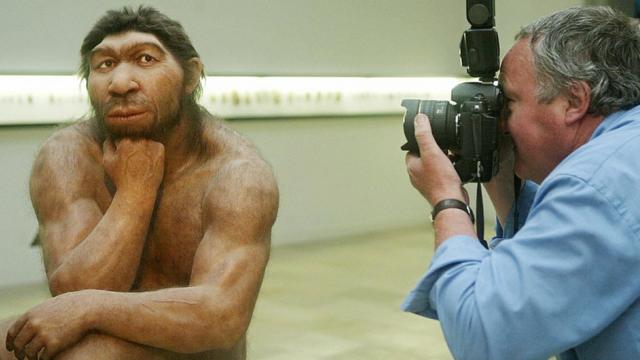 Hombre fotografiando una reproducción de un neandertal.