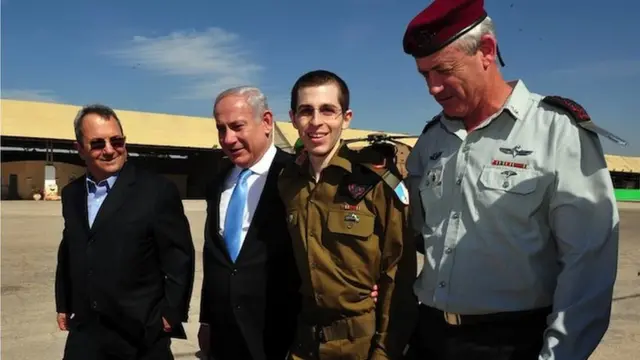 In this handout photo provided by the Israeli Defense Force, freed Israeli soldier Gilad Shalit (2nd R) walks with Defence Minister Ehud Barak (L), Israeli Prime Minister Benjamin Netanyahu (2nd, L) and IDF Chief of General Staff Benny Gantz (R) at Tel Nof Airbase on 18 October 2011 in central Israel