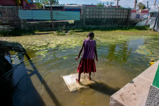 মোজাম্বিকের বেইরাতে একটি স্কুলের প্লাবিত চত্বরে এক টুকরো কাঠের ওপর দাঁড়িয়ে আছে একটি কিশোরী। ২৭শে জানুয়ারি ২০২১