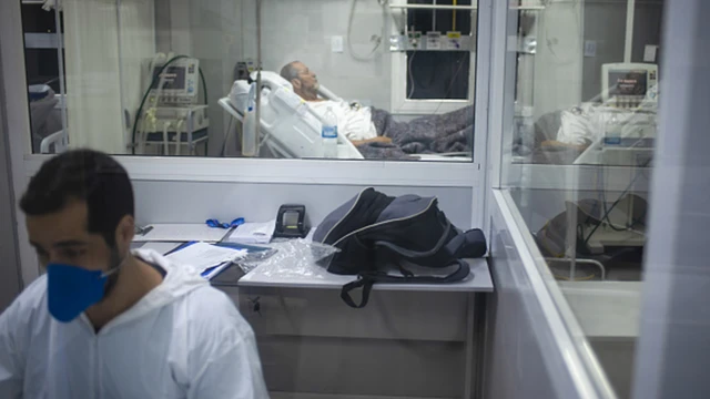 Profissional da saúde trabalha com paciente em maca ao fundo