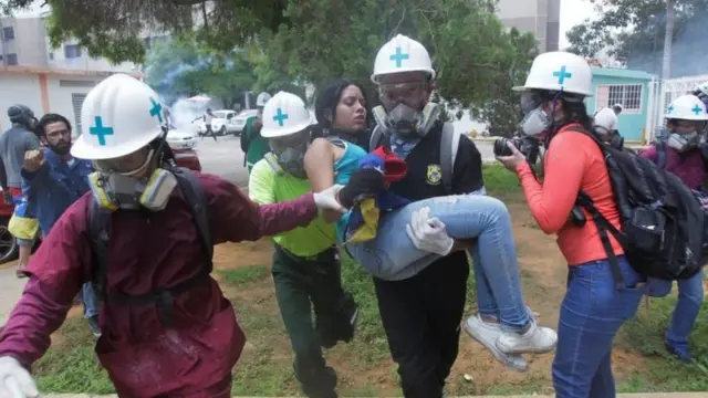 Una joven es cargada tras sufrir los efectos de gases lacrimógenos en una protesta en Maracaibo, el 18 de mayo de 2017