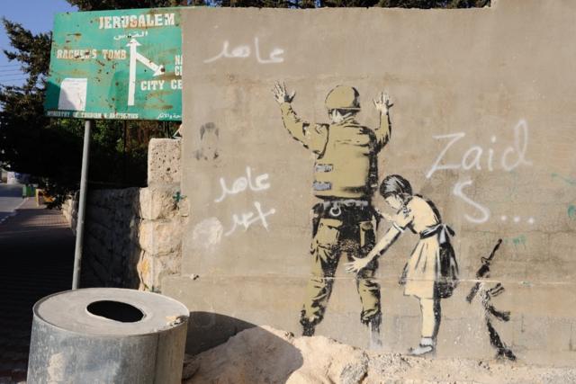 An Israeli soldier walks past a Banksy graffitti mural in Bethlehem. The Islamic Jihad faction organized protests in solidarity with Gaza, in the West Bank city of Bethlehem. As ceasefire talks collapsed completely in Cairo earlier this week, and fighting renewed on Wednesday. Hamas launched a barrage of rockets towards Southern Israel, some reaching as far as Jerusalem and illegal Israeli settlements in the West Bank, some 80 kilometers away from Gaza. Late Tuesday evening an Israeli missile struck the home of Hamas military commander Muhammad Deif, killing his wife and three-year-old daughter. Deif, according to Hamas reports was not assassinated. On Thursday, three more to military commanders, Muhammad Abu Shammala, Raed al-Attar and Muhammad Barhoum were also killed in airstrikes. In response, Hamas killed what they believed to be collaborators with Israel in Gaza. 18 suspected of having worked with Israeli army intelligence have been killed so far. Late Friday afternoon, a four-ye