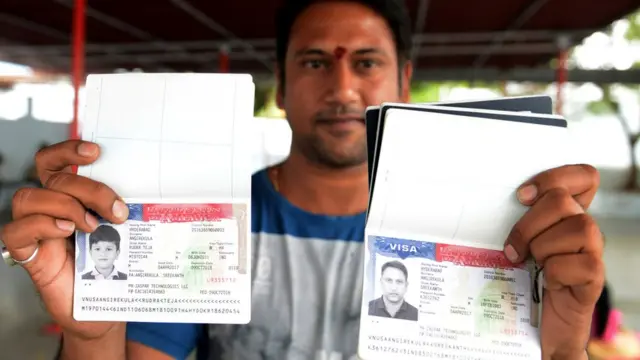 યુએસના વિઝાના સ્ટેમ્પ સાથે પાસપોર્ટ દર્શાવતો વ્યક્તિ