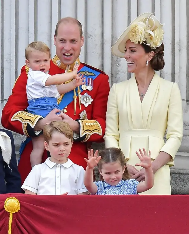 Prince William, Duke of Cambridge holding Prince Louis, Prince George, Princess Charlotte and Britain"s Catherine, Duchess of Cambridge stand with other members of the Royal Family on the balcony of Buckingham Palace to watch a fly-past of aircraft by the Royal Air Force, in London on June 8, 2019