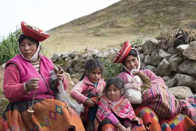 Quechua women and two young girls pose for the camera in the stunning, handmade clothing, Lares Valley, Peru, May 2016.