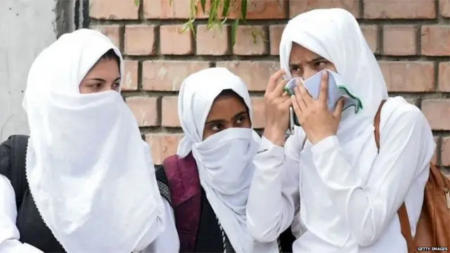 मुंह ढककर खड़ीं लड़कियां