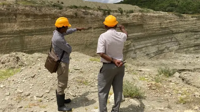 Deux hommes portant un casque de sécurité pointent vers des rochers