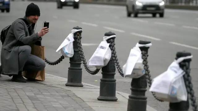 Мужчина фотографирует продуктовые пакеты