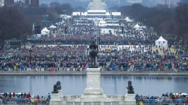 ประชาชนพากันจับจองที่บริเวณลานเนชั่นแนลมอลล์ ที่อยู่ด้านหน้าอาคารรัฐสภา เพื่อจะได้ชมพิธีสาบานตน ท่ามกลางสภาพอากาศหนาวและฝนที่โปรยปรายลงมา