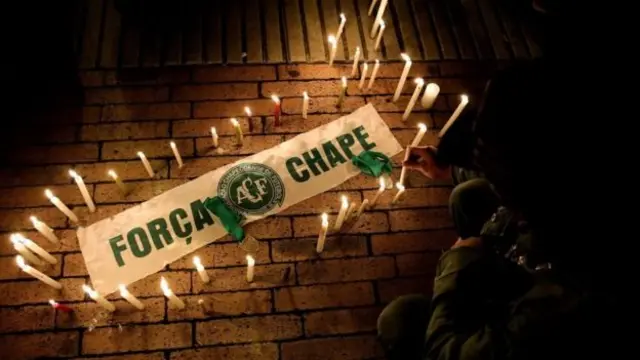 Un cartel rodeado de velas y el texto: "Fuerza Chape".
