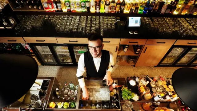 Барна стійка, бармен і багато склянок