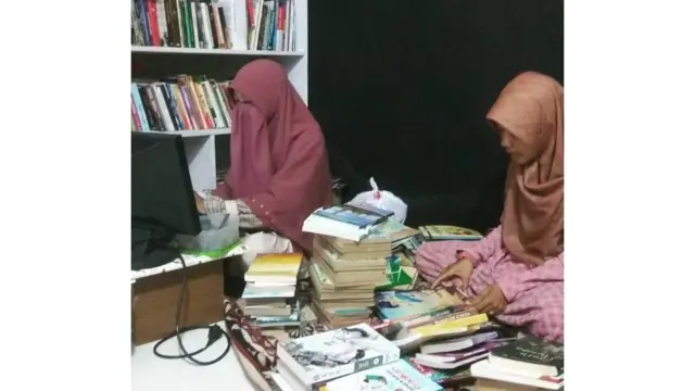 Dua relawan sedang merekap buku koleksi Buku Ini Aku Pinjam.