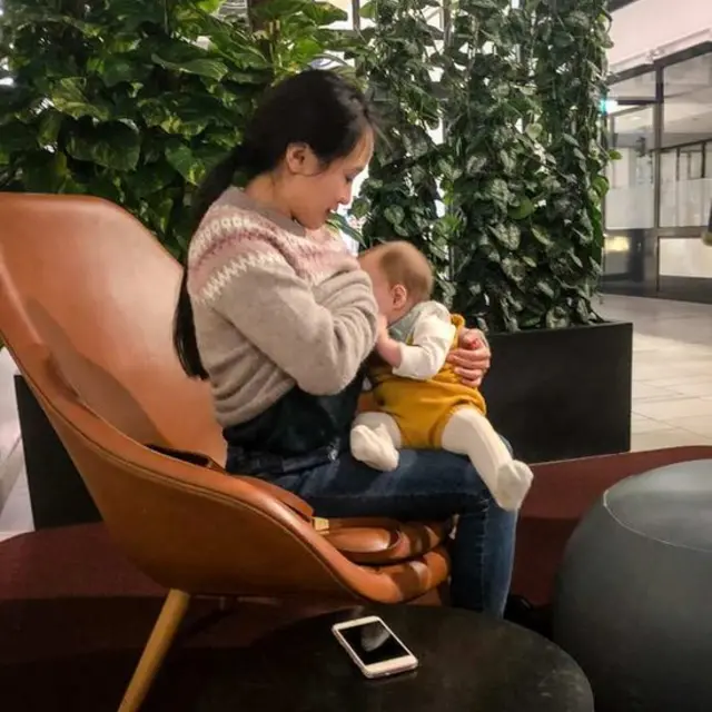 Ibu menyusui anaknya di sebuah pusat keramaian.