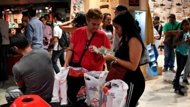 Em shopping, duas mulheres mexem com notaskundenservice bwindólares